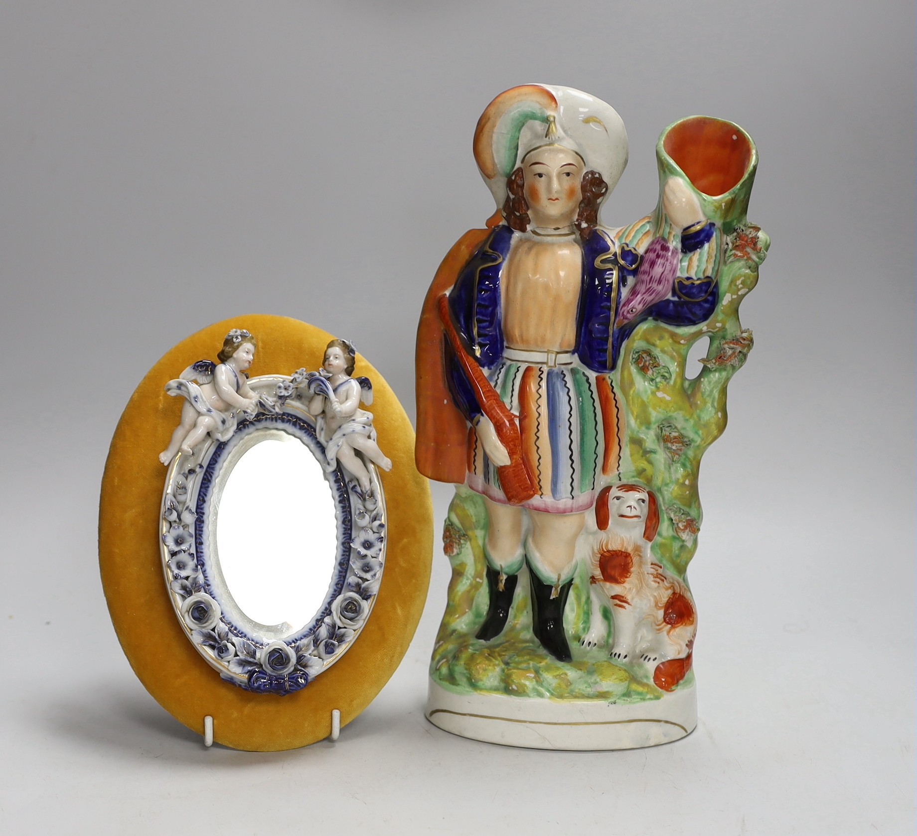 A porcelain floral encrusted and putti oval mirror mounted on gold velvet and a Staffordshire figural flatback, flatback 29cms high